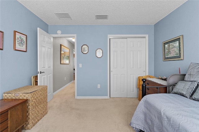 17913 SE 88th Cascade Ct, The Villages, FL 32162 - bedroom with a closet, a textured ceiling, visible vents, baseboards, and light colored carpet