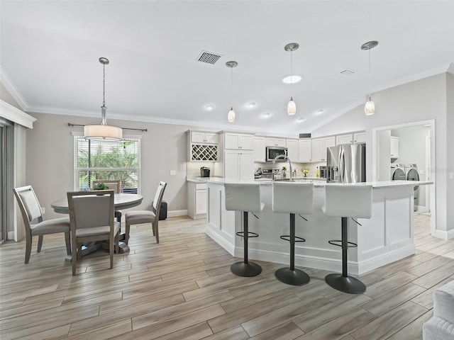 kitchen featuring stainless steel appliances, visible vents, light countertops, wood tiled floor, and washing machine and clothes dryer