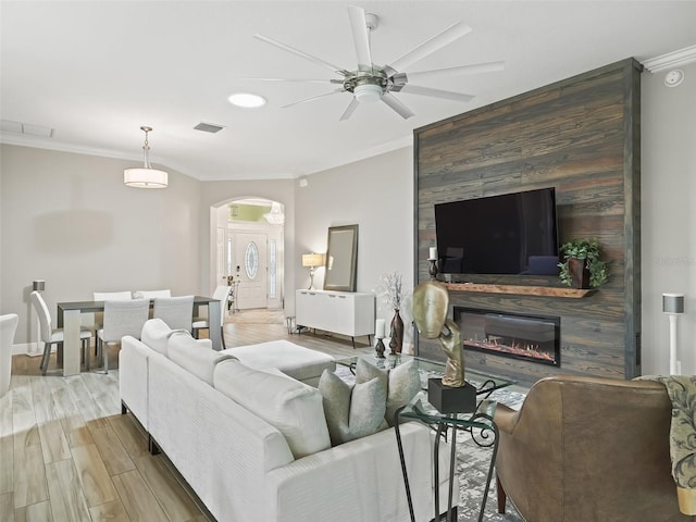 living room with light hardwood / wood-style floors, ornamental molding, and ceiling fan