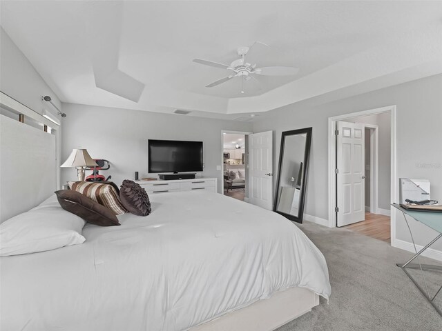 carpeted bedroom featuring a raised ceiling and ceiling fan