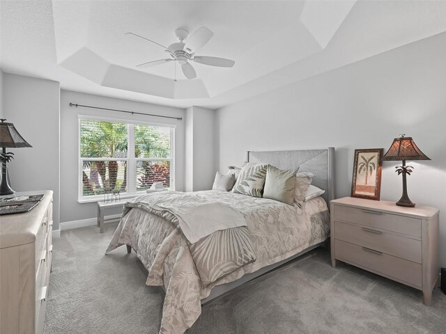 bedroom featuring ceiling fan, a tray ceiling, and dark colored carpet