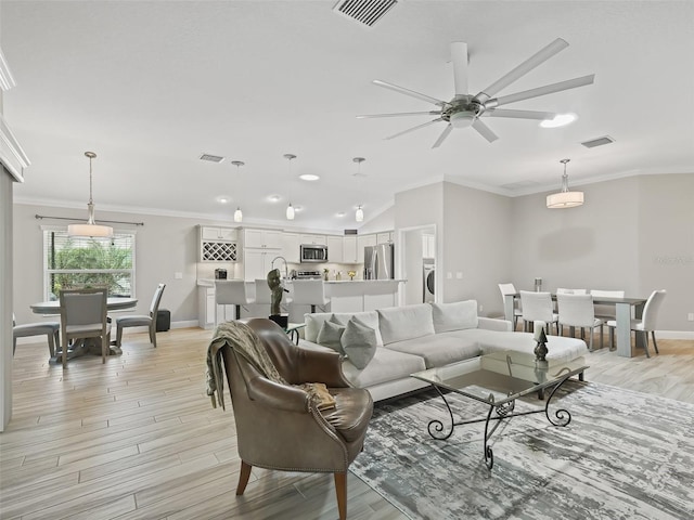 living room featuring light hardwood / wood-style floors, crown molding, washer / dryer, and ceiling fan