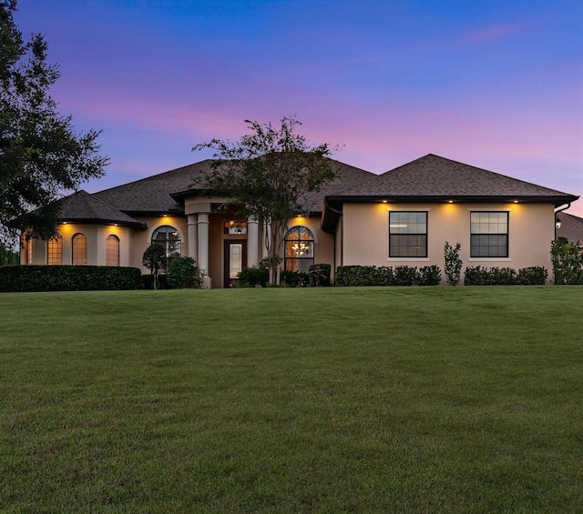 view of front facade with a lawn and stucco siding