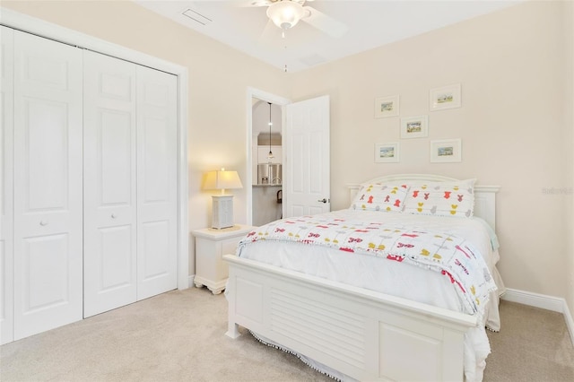 bedroom featuring a ceiling fan, a closet, light colored carpet, and baseboards