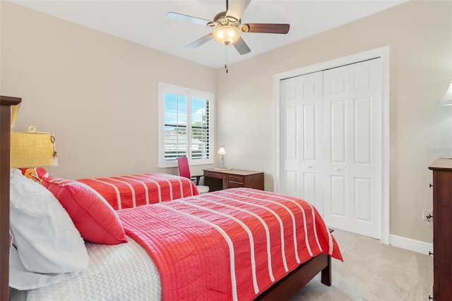 bedroom featuring a ceiling fan, a closet, light colored carpet, and baseboards