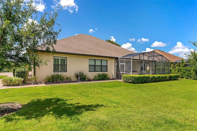 rear view of house with a lanai, a lawn, and stucco siding