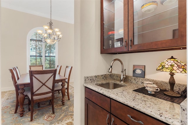 interior space with hanging light fixtures, ornamental molding, a sink, a chandelier, and baseboards