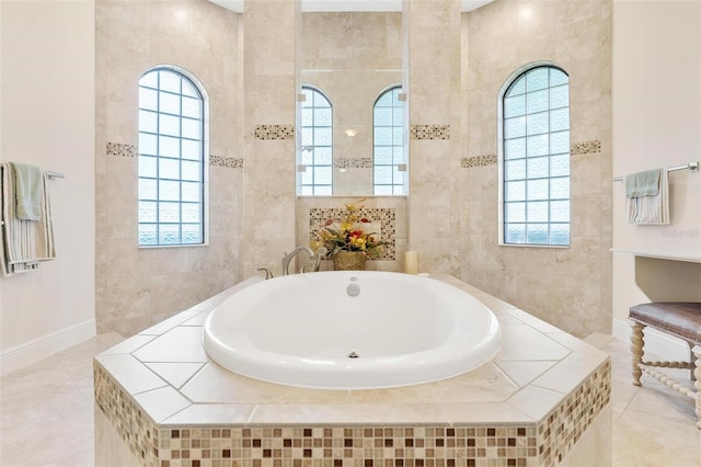 bathroom with tile patterned floors, tile walls, baseboards, and a bath