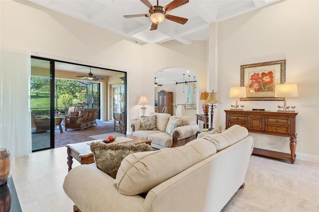 living area with arched walkways, ceiling fan, coffered ceiling, and a towering ceiling