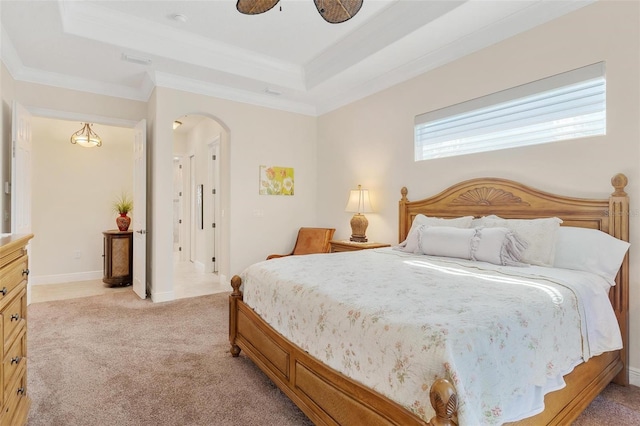 bedroom with light carpet, baseboards, arched walkways, a raised ceiling, and crown molding