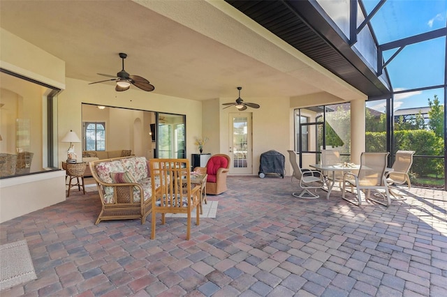 view of patio with a lanai, outdoor dining area, ceiling fan, and an outdoor living space