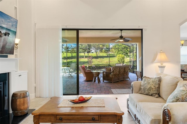 living room featuring ceiling fan and a glass covered fireplace