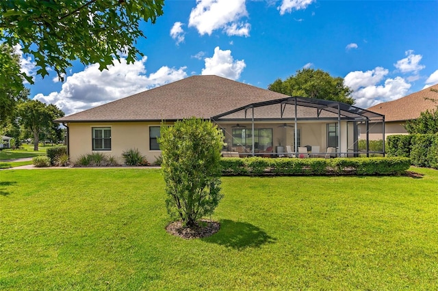 back of house with a yard, a lanai, a ceiling fan, and stucco siding