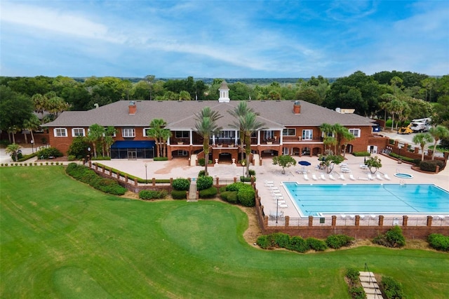 community pool featuring a patio, a lawn, and fence