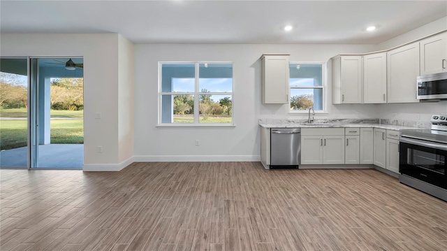 kitchen featuring stainless steel appliances, a wealth of natural light, white cabinets, and light hardwood / wood-style floors