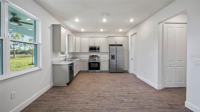 kitchen featuring stainless steel appliances, light hardwood / wood-style floors, sink, light stone countertops, and ceiling fan