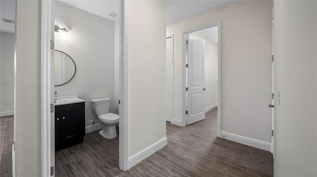 bathroom featuring toilet, vanity, and wood-type flooring