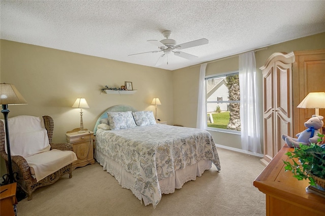 bedroom featuring light carpet, a textured ceiling, a ceiling fan, and baseboards