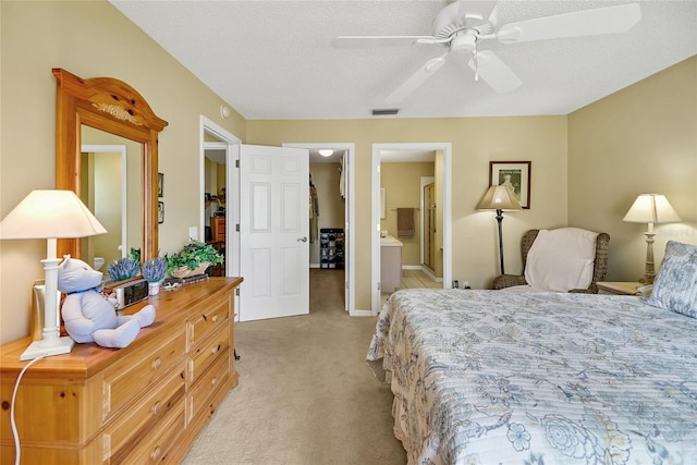 bedroom featuring visible vents, light carpet, connected bathroom, a textured ceiling, and ceiling fan