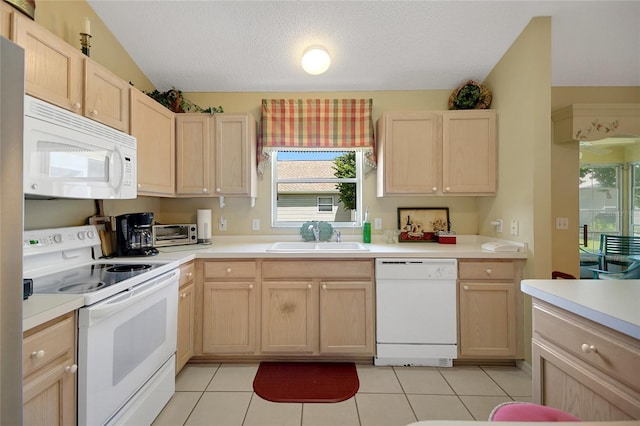 kitchen with white appliances, light countertops, a textured ceiling, light brown cabinetry, and a sink