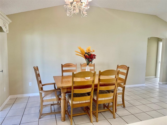 dining area featuring arched walkways, a notable chandelier, light tile patterned floors, vaulted ceiling, and baseboards