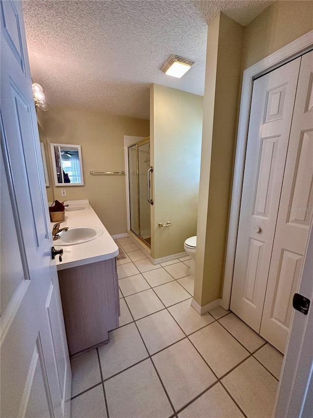 bathroom featuring toilet, a sink, tile patterned floors, double vanity, and a stall shower