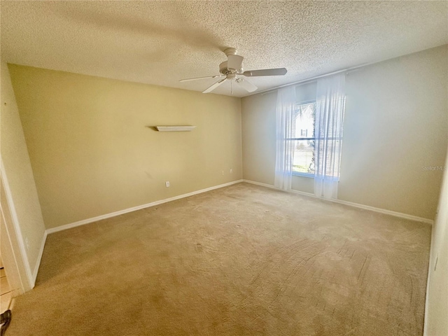 carpeted empty room featuring ceiling fan, baseboards, and a textured ceiling