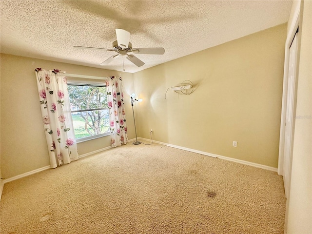 carpeted empty room with a textured ceiling, baseboards, and a ceiling fan