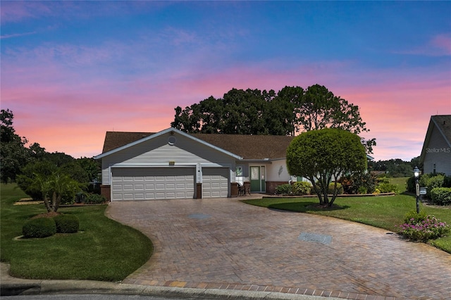 ranch-style home with a garage and a lawn