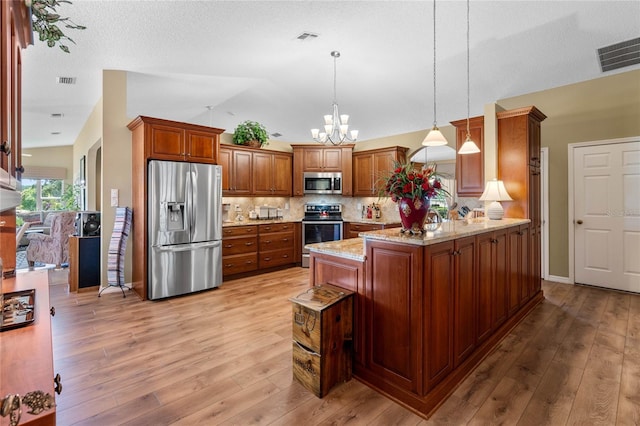 kitchen with pendant lighting, stainless steel appliances, light hardwood / wood-style floors, and kitchen peninsula