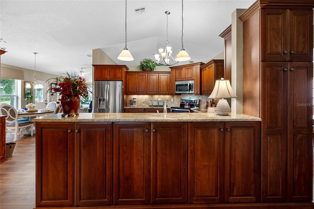 kitchen featuring vaulted ceiling, light wood-type flooring, appliances with stainless steel finishes, light stone counters, and a notable chandelier