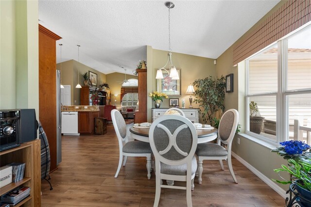 dining space featuring vaulted ceiling, dark hardwood / wood-style flooring, a notable chandelier, and a textured ceiling