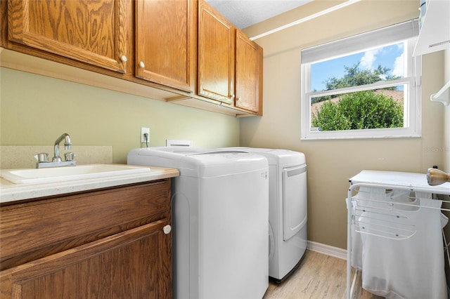 washroom featuring cabinets, washer and clothes dryer, sink, and light hardwood / wood-style floors