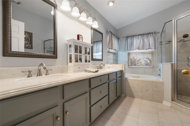 bathroom with independent shower and bath, vaulted ceiling, and vanity