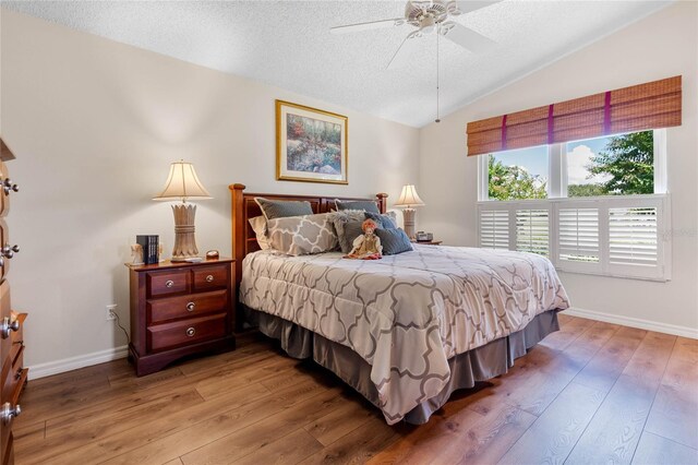 bedroom featuring lofted ceiling, hardwood / wood-style flooring, ceiling fan, and a textured ceiling