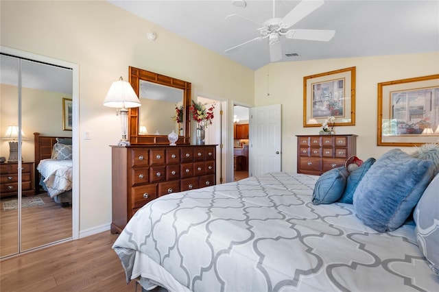 bedroom with ceiling fan, a closet, wood-type flooring, and vaulted ceiling