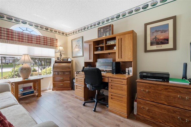 office area with a textured ceiling and light hardwood / wood-style floors