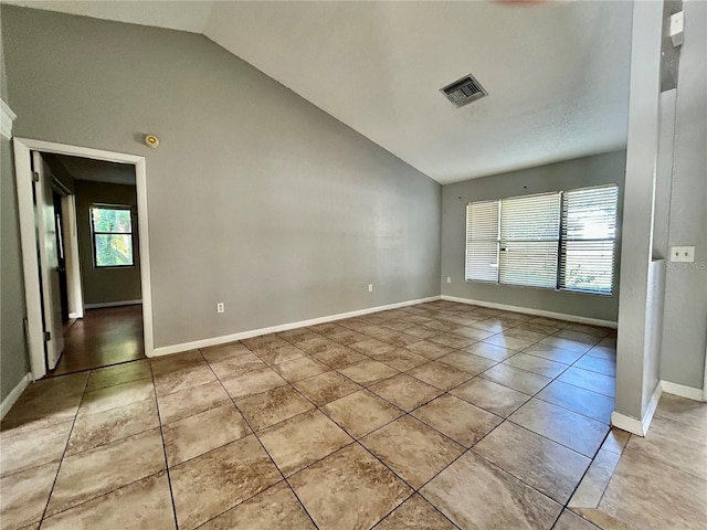 spare room featuring vaulted ceiling and light tile patterned floors