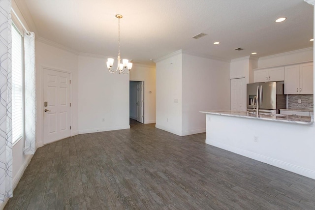 kitchen featuring an inviting chandelier, stainless steel fridge, backsplash, decorative light fixtures, and white cabinets