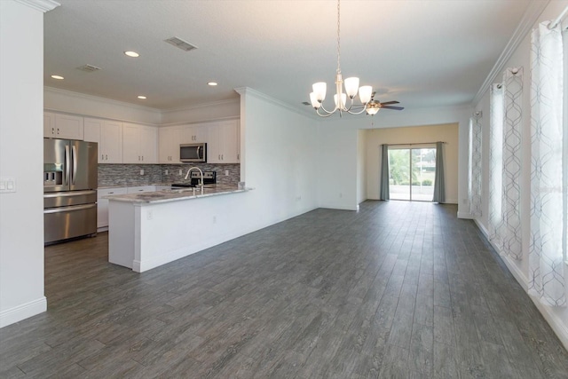 kitchen featuring pendant lighting, appliances with stainless steel finishes, white cabinetry, backsplash, and kitchen peninsula