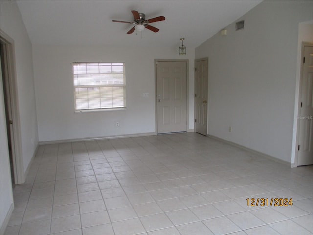 tiled empty room with ceiling fan and vaulted ceiling