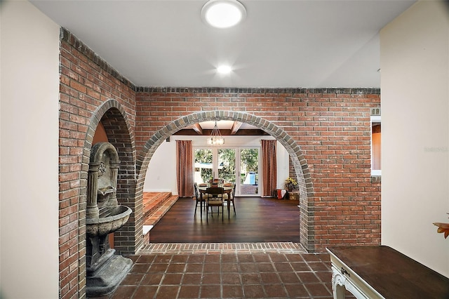 hallway with an inviting chandelier and brick wall