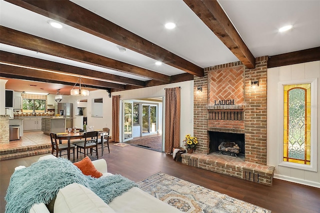 living room with beamed ceiling, hardwood / wood-style floors, and a brick fireplace