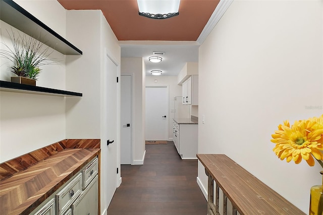 hallway featuring dark wood-style floors, visible vents, and crown molding