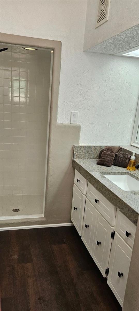 bathroom with visible vents, a textured wall, vanity, a shower stall, and wood finished floors