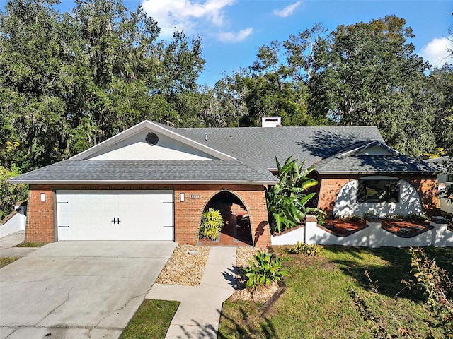 ranch-style house with a shingled roof, concrete driveway, brick siding, and an attached garage