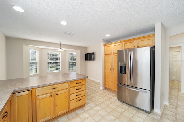 kitchen featuring a textured ceiling, pendant lighting, and stainless steel fridge