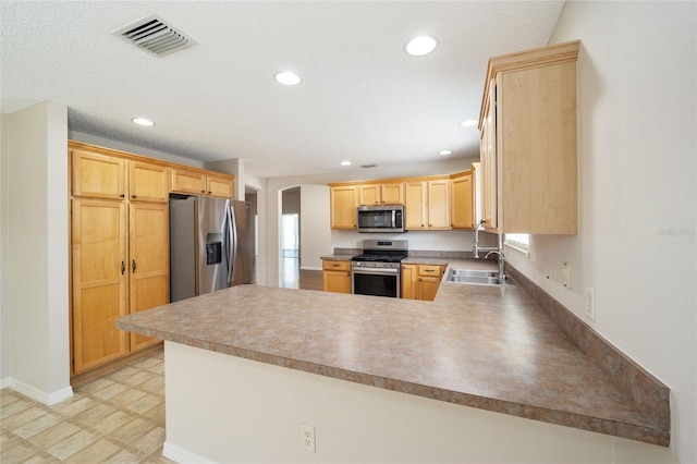 kitchen featuring light brown cabinetry, appliances with stainless steel finishes, sink, a textured ceiling, and kitchen peninsula