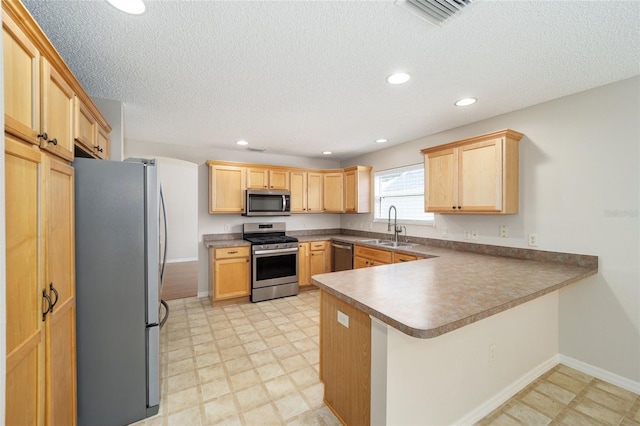 kitchen with a textured ceiling, appliances with stainless steel finishes, sink, and kitchen peninsula