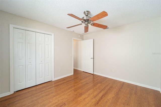 unfurnished bedroom featuring a closet, hardwood / wood-style floors, a textured ceiling, and ceiling fan